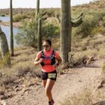 Woman running on desert trail with cacti