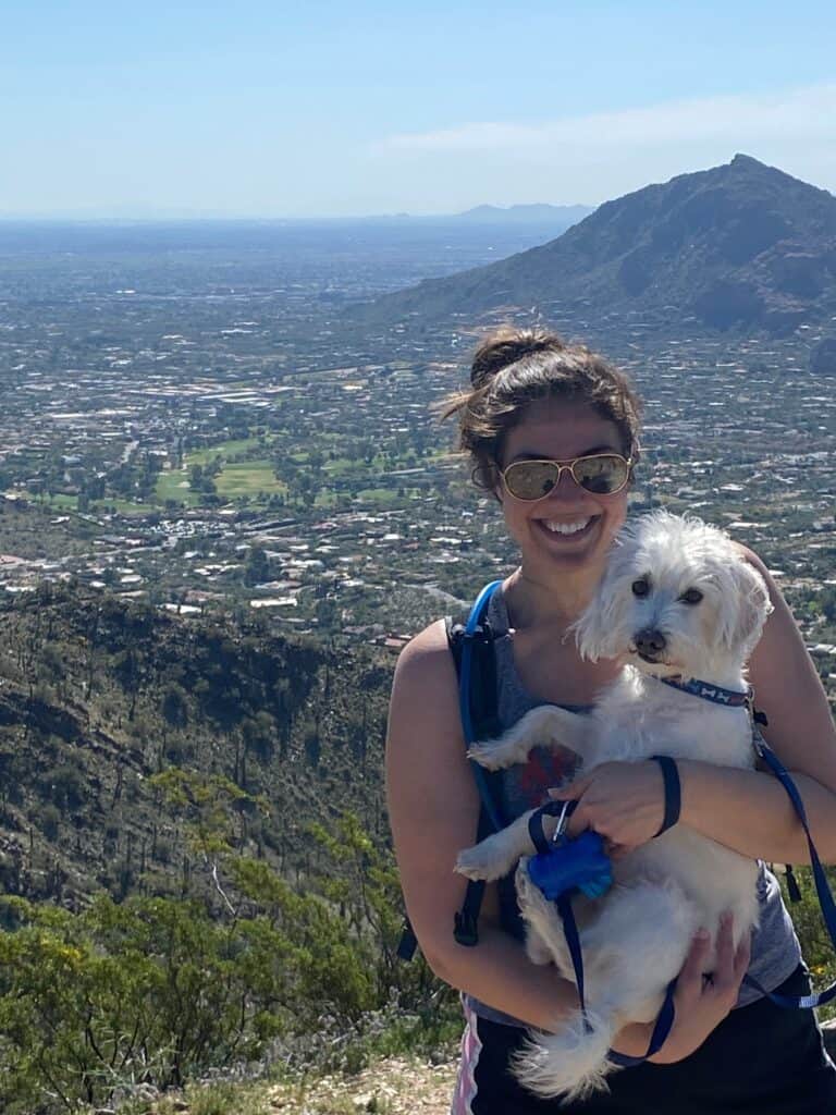 Woman hiking with dog, mountain view background.