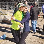 Two women hugging at outdoor race event.
