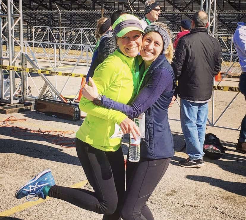 Two women hugging at a race event.