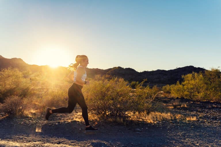Woman jogging at sunrise in desert landscape.